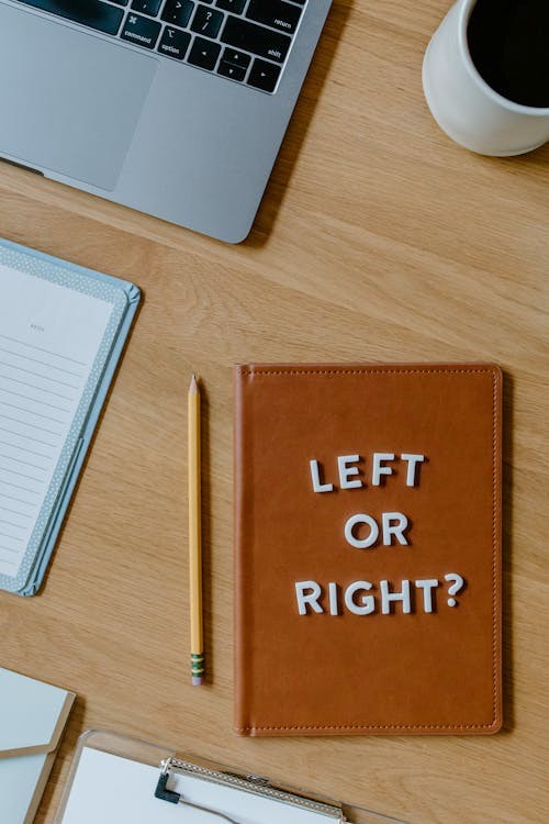 brown notebook with text beside a pencil on wooden table