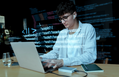 A young male programmer wearing glasses and earphones, working on a laptop with lines of code digitally overlaid on the image.